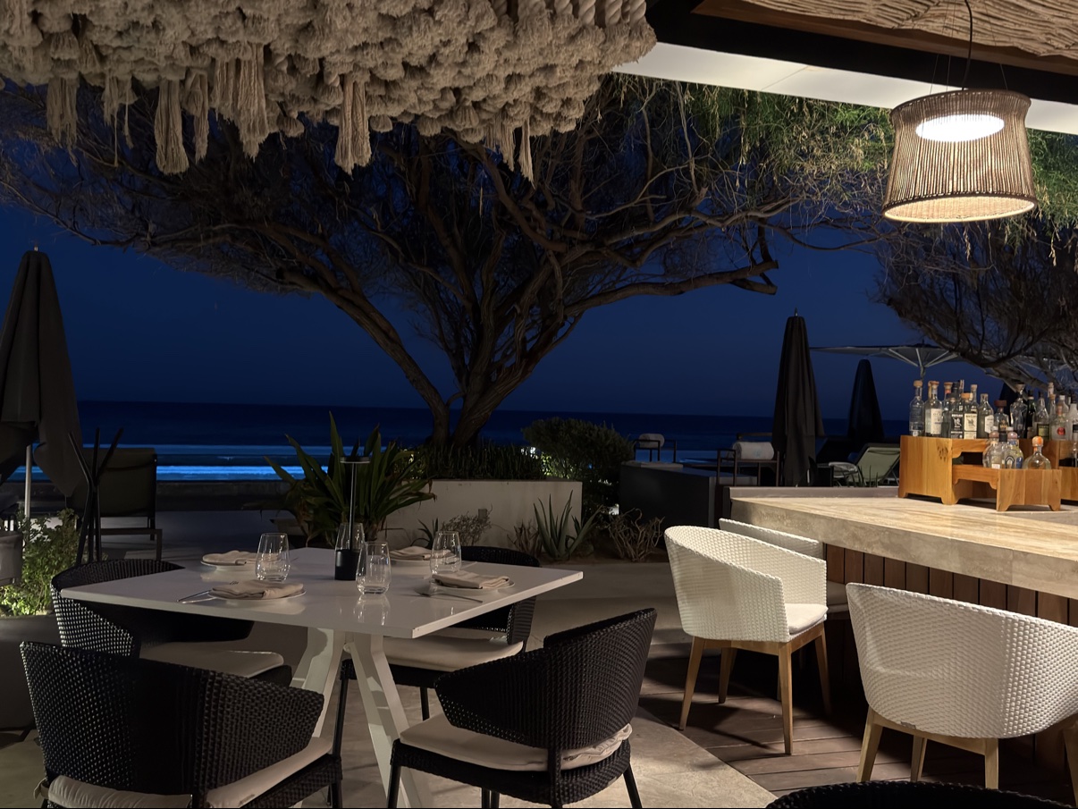 The Riccio di Mare terrace at dusk, with the ocean behind and the bar at right.