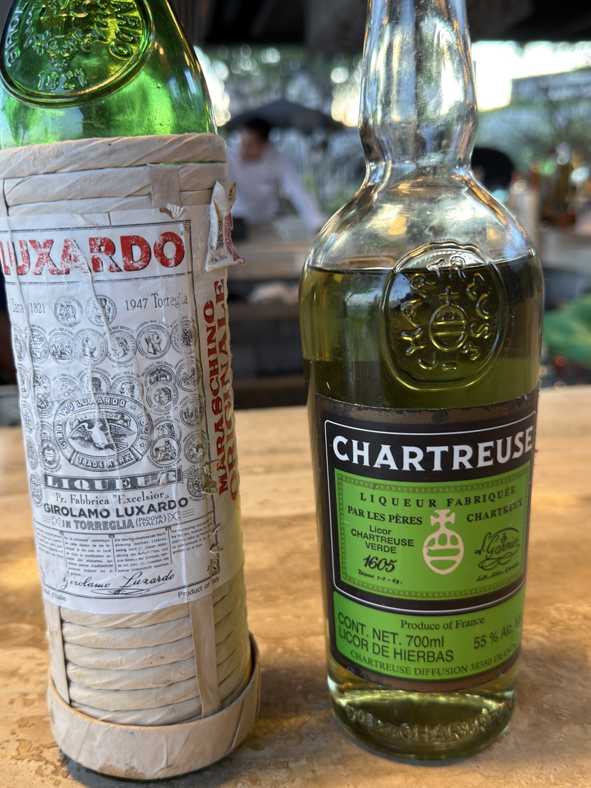 The genuine articles: Luxardo Maraschino in its straw wrap, and Green Chartreuse.