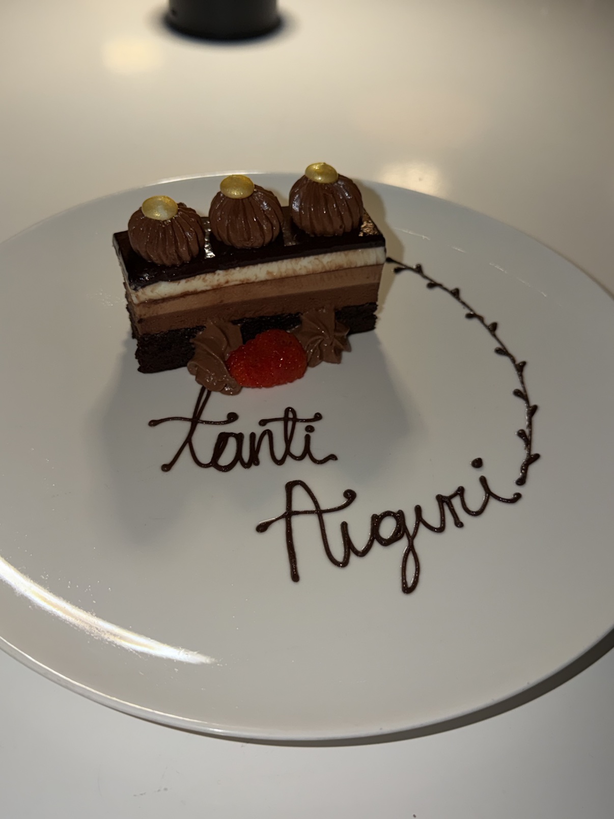 Chocolate dessert with 'Tanti Auguri' piped across the plate.